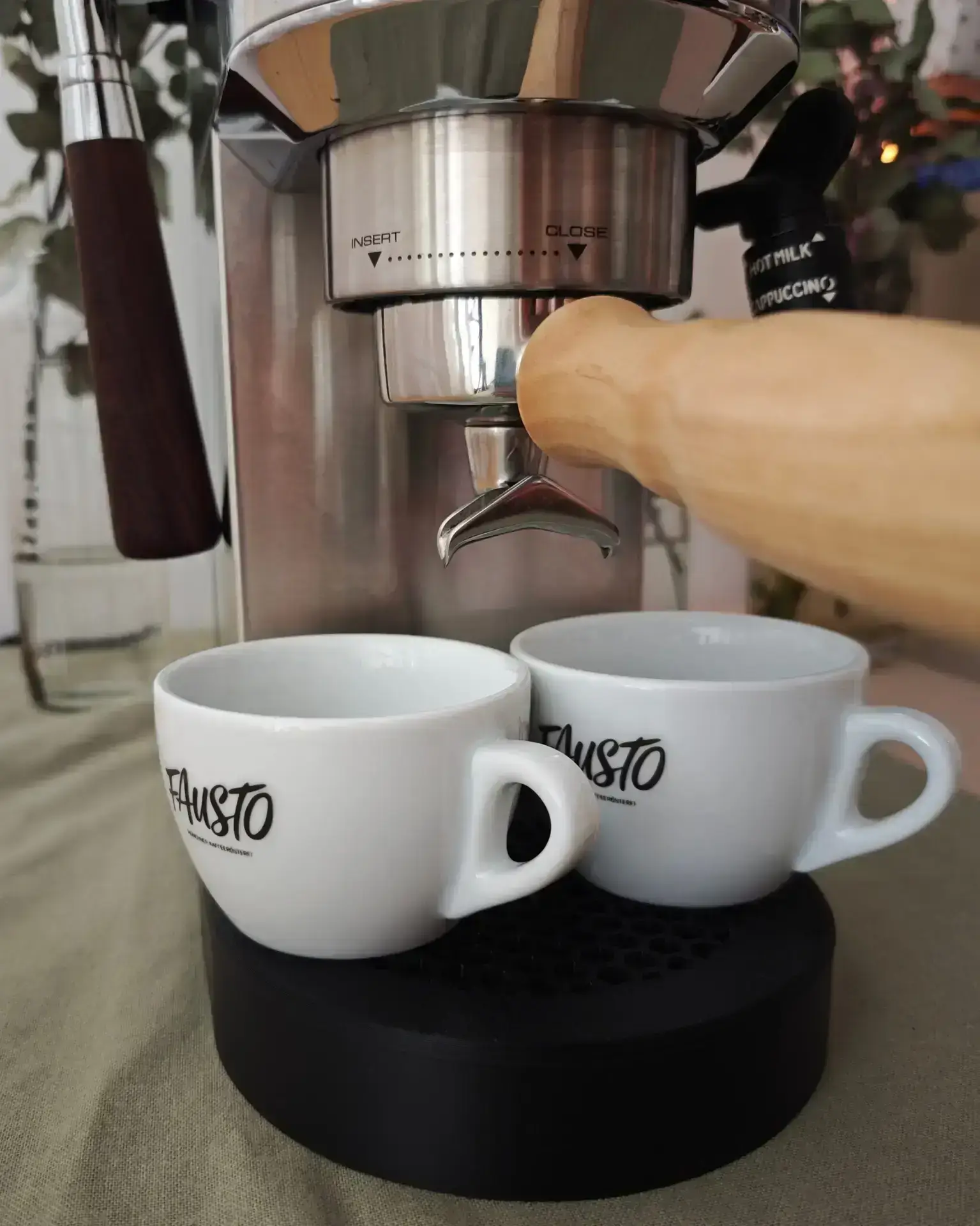 Zwei weiße Espressotassen stehen nebeneinander auf der magnetischen Abtropfschale unter dem Auslauf