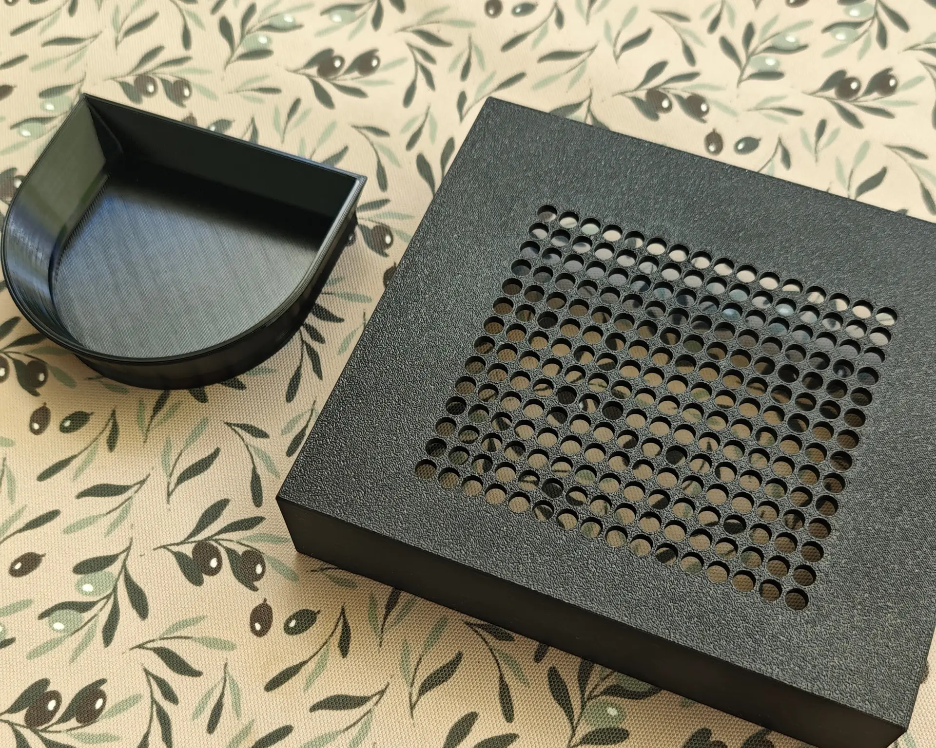 The Slim drip tray and the removed PETG container on patterned fabric