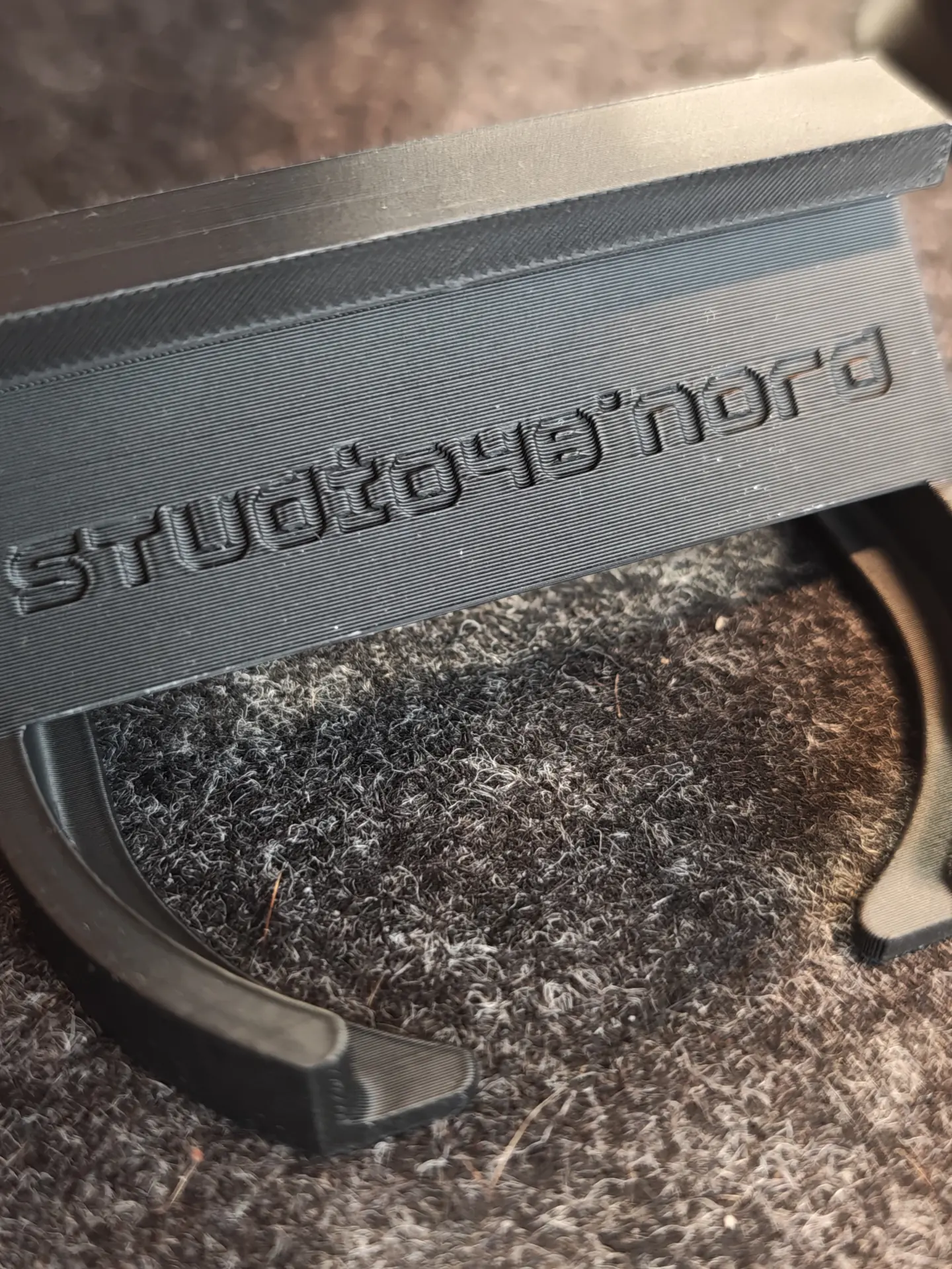 Nahaufnahme der Oberkante des schwarzen Siebträgerhalters, das Logo studio 48° nord ist in die Druckschichten eingeprägt und zeichnet sich als Schattenrelief ab