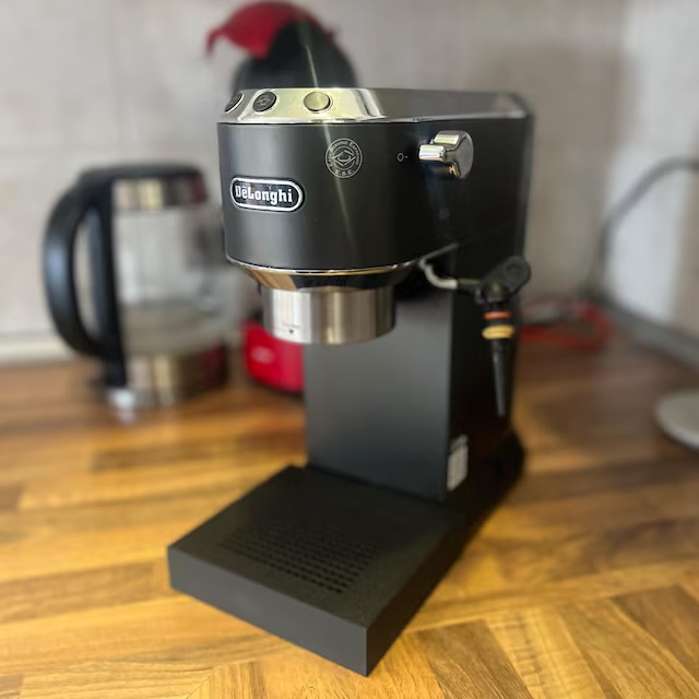 De'Longhi Dedica nera con vaschetta raccogligocce Slim su un piano di lavoro della cucina in legno