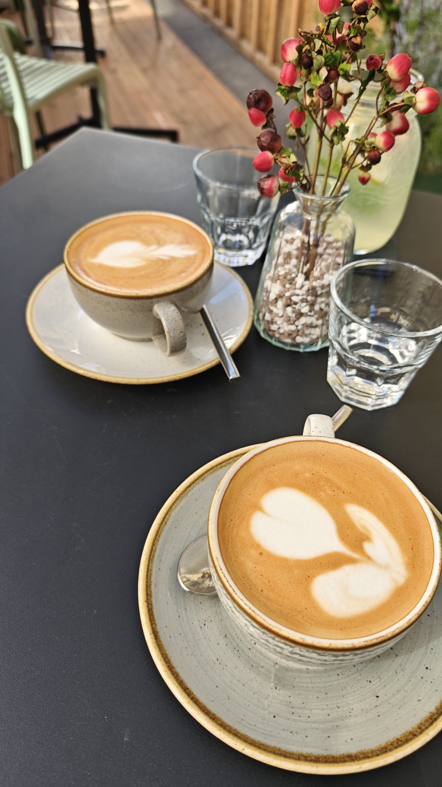 Due cappuccini con latte art su un tavolino da caffè con fiori